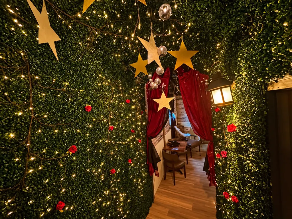 Ivy-covered entryway with fairy lights, gold stars and red curtains at The Oak & Ivy Taphouse